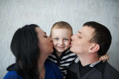 mom and dad kiss son at homeの写真素材