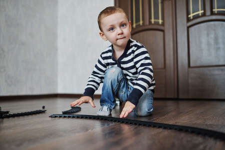 photo of little happy boy builds toy railroadの写真素材