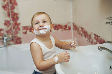 photo of little boy playing with shaving foamの写真素材