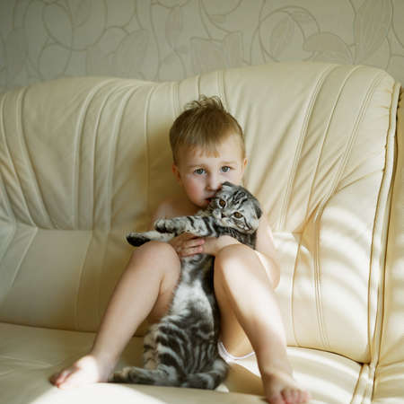 photo of little funny boy hugs cat portraitの写真素材