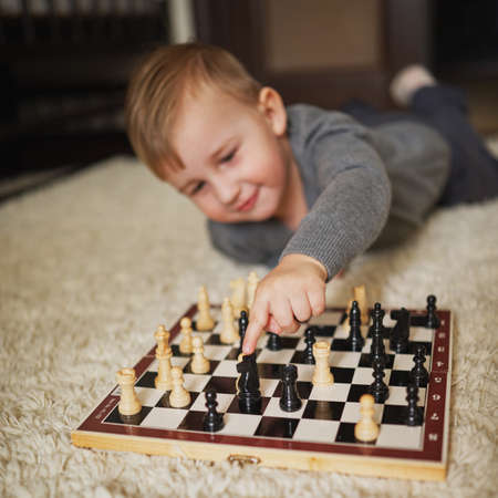 little boy plays chess lying on the floorの写真素材