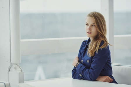 Beautiful blond girl sits in caffee at tableの写真素材