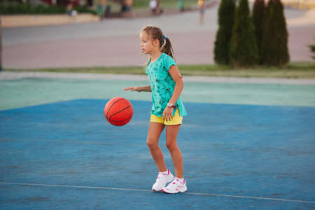 photo of little cute girl playing basketball outdoorsの写真素材