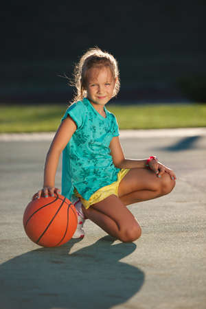 photo of little cute girl playing basketball outdoorsの写真素材