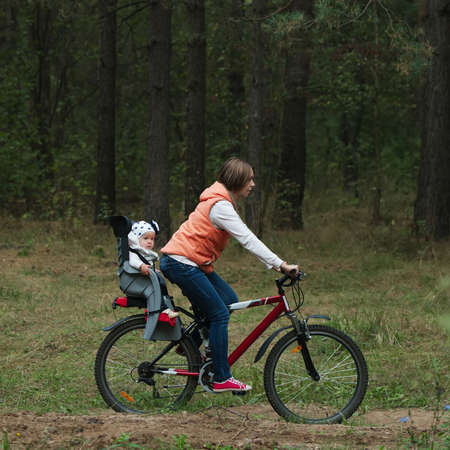 happy mother and daughter riding bike in the forestの写真素材