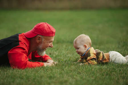 happy grandfather and grandson lying on grassの写真素材