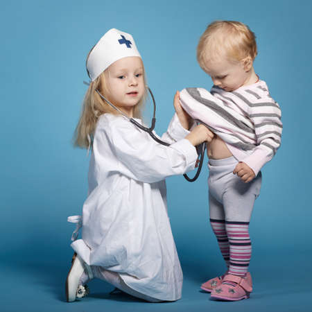 two cute little girls playing doctor. studio photoの写真素材