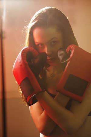 beautiful girl in boxing gloves kick punching bagの写真素材