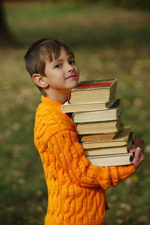 photo of little happy boy carrying stack of booksの写真素材