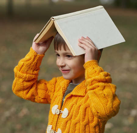little funny boy with book on his head