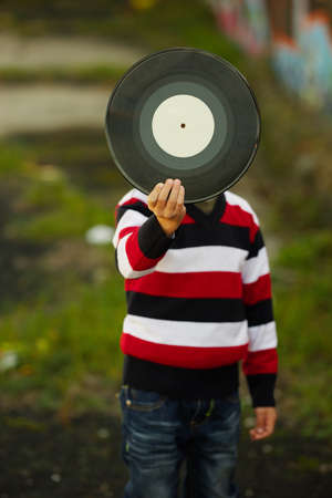 photo of little boy hiding behind vinyl plateの写真素材