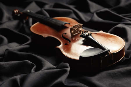 aged violin on dark silk fabric textureの写真素材