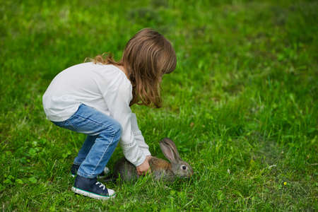 photo of cute little girl with rabbit on grassの写真素材