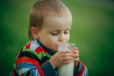 photo of little funny boy with glass of milkの写真素材