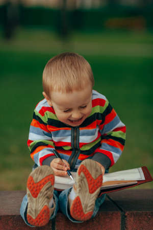 photo of little funny boy writing with pen