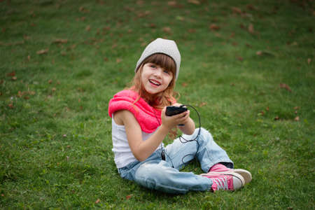 photo of little girl with mobile phone on the grassの写真素材
