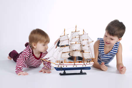 boy and girl playing with ship on whiteの写真素材