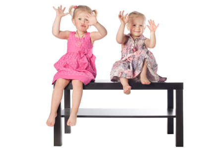 two funny girls scaring sitting on the tableの写真素材