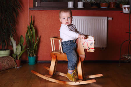 photo of cute boy riding wooden horseの写真素材