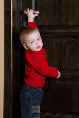 little boy tries to open door at homeの写真素材