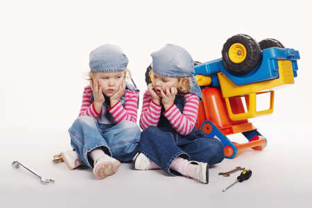 cute little twin girls repairing carの写真素材