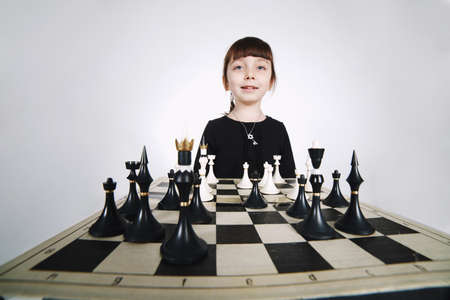 little girl playing chess on white