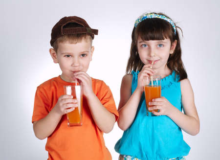 little boy and girl drinking juiceの写真素材