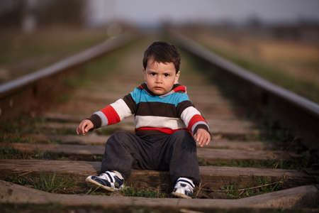 little beautiful boy plays on railroadの写真素材