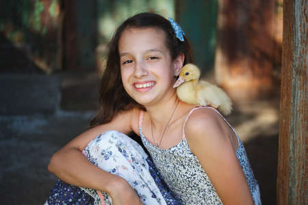 girl with little yellow duckling in summer villageの写真素材