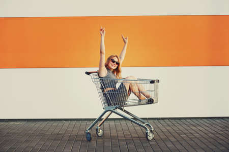 beautiful blonde girl sitting in shopping basketの写真素材