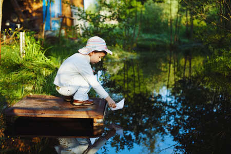 girl plays with paper boat in the riverの写真素材