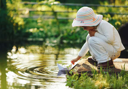 girl plays with paper boat in the riverの写真素材