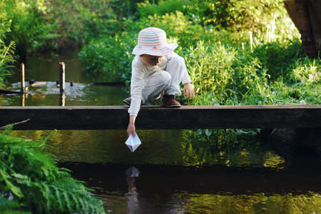 girl plays with paper boat in the riverの写真素材