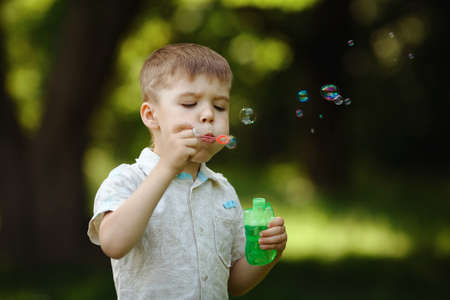 boy inflates bubbles in summer parkの写真素材