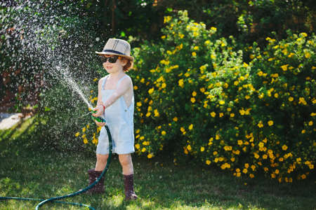cute little boy watering the garden with hoseの写真素材