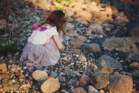 little girl playing on stones beachの写真素材