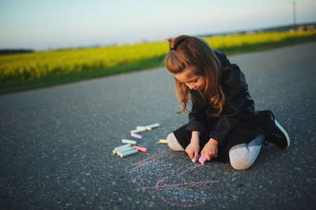 little girl draws pictures on asphaltの写真素材