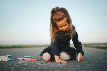 little girl draws pictures on asphaltの写真素材