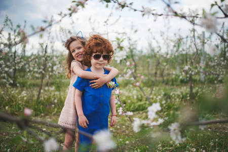 little boy and girl in blooming gardenの写真素材