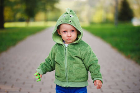 little unhappy boy with dinosaur costumeの写真素材