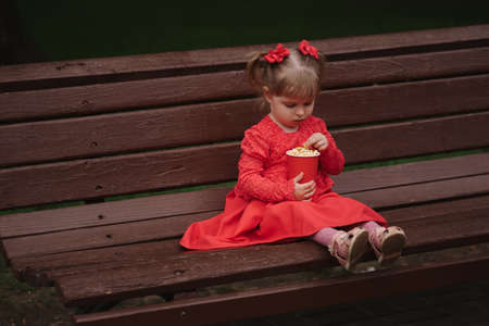 little girl with cup of popcorn in parkの写真素材