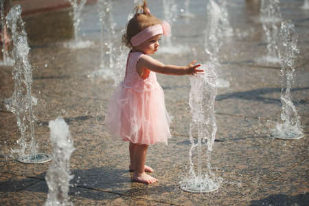 little girl plays with water in fountainの写真素材