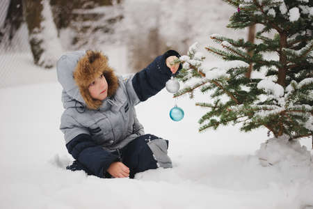 boy decorating christmas tree n the yard