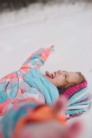 little girl catching snowflakes in winter parkの写真素材