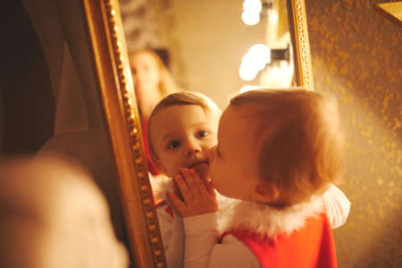 little girl kisses herself in the mirrorの写真素材