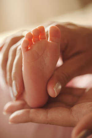 mother holds little foot of newborn babyの写真素材