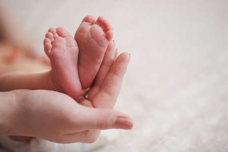 mother holds cute little foot of newborn babyの写真素材