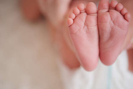 mother holds little foot of newborn baby