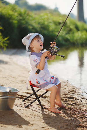 happy girl with rod on coast of river