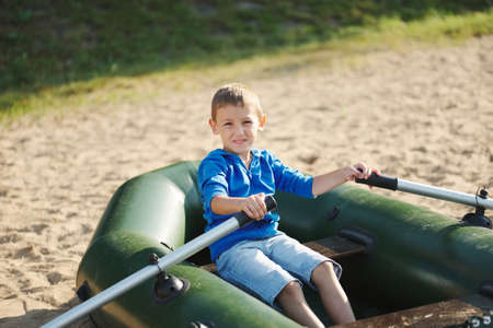 little boy swimming in boat on sandy beachの写真素材